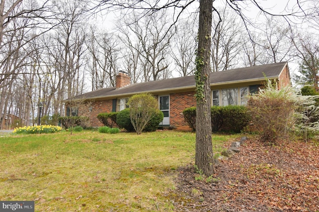 ranch-style home featuring brick siding, a chimney, and a front lawn