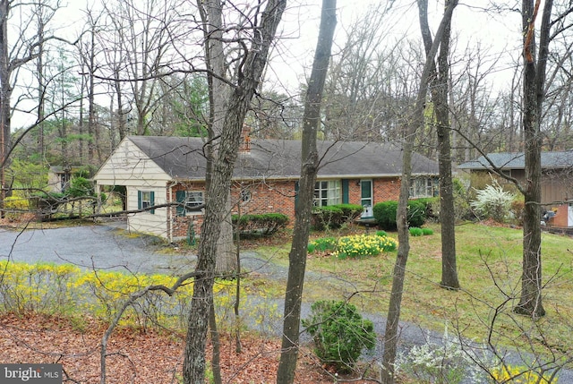 view of front of house featuring brick siding and roof with shingles