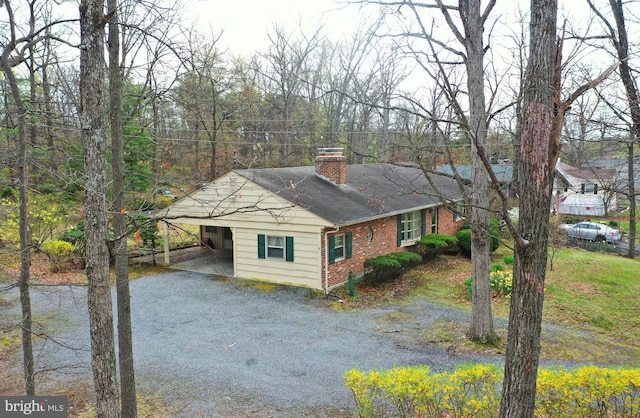 view of front of home with a shingled roof, a chimney, and driveway