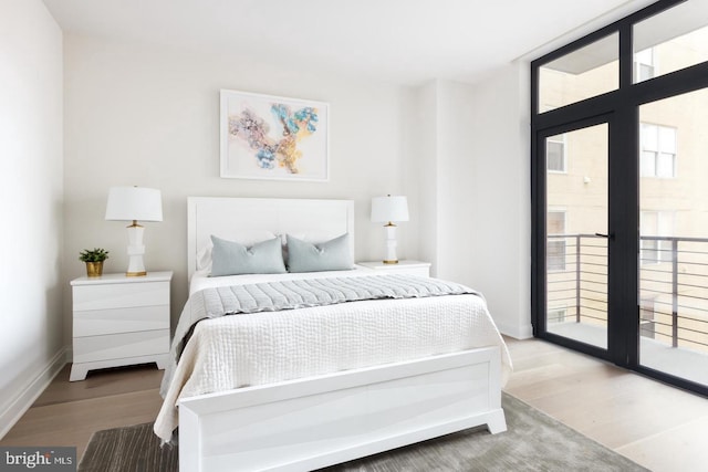 bedroom with wood finished floors, access to outside, baseboards, and french doors
