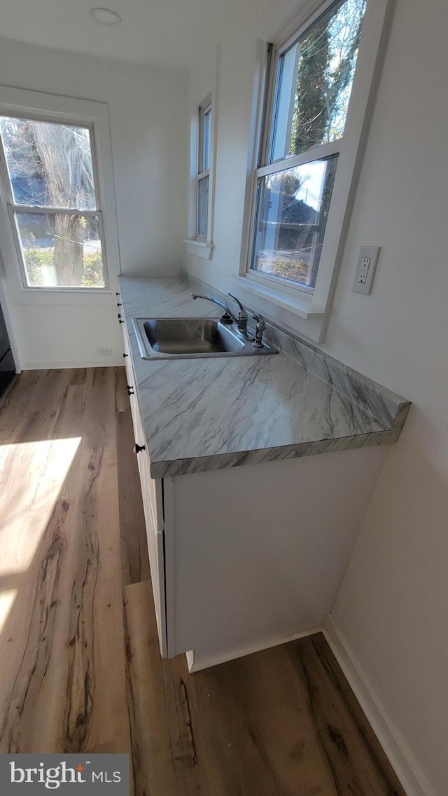 kitchen with light countertops, a sink, and wood finished floors