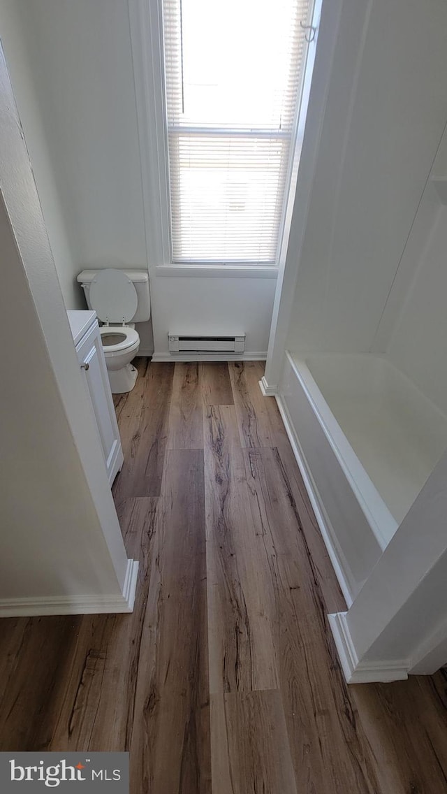 full bath with a bathtub, toilet, a shower, a baseboard radiator, and wood finished floors
