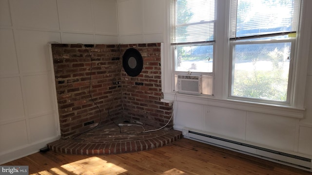 room details featuring a decorative wall, cooling unit, wood finished floors, and baseboard heating