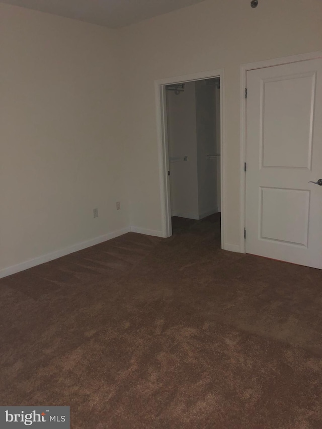 empty room featuring dark carpet and baseboards
