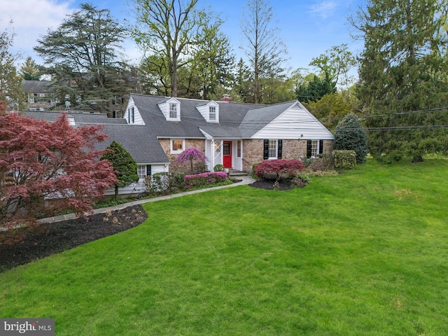 cape cod house with a front yard, stone siding, and a chimney