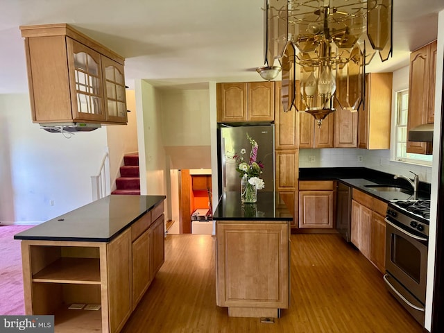 kitchen with stainless steel appliances, a kitchen island, a sink, and dark countertops