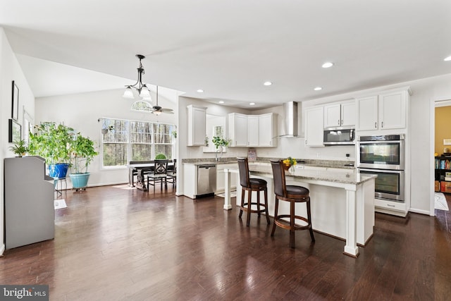 kitchen featuring white cabinets, appliances with stainless steel finishes, wall chimney range hood, and a sink