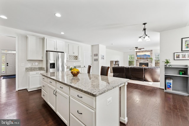 kitchen featuring dark wood-style flooring, a fireplace, ceiling fan, white cabinets, and stainless steel fridge with ice dispenser