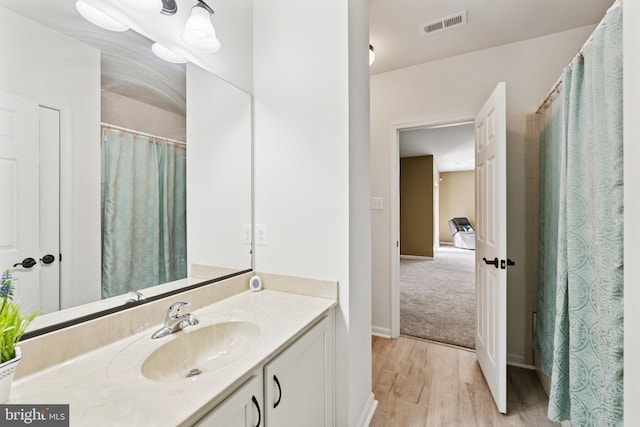 bathroom featuring vanity, visible vents, wood finished floors, and baseboards