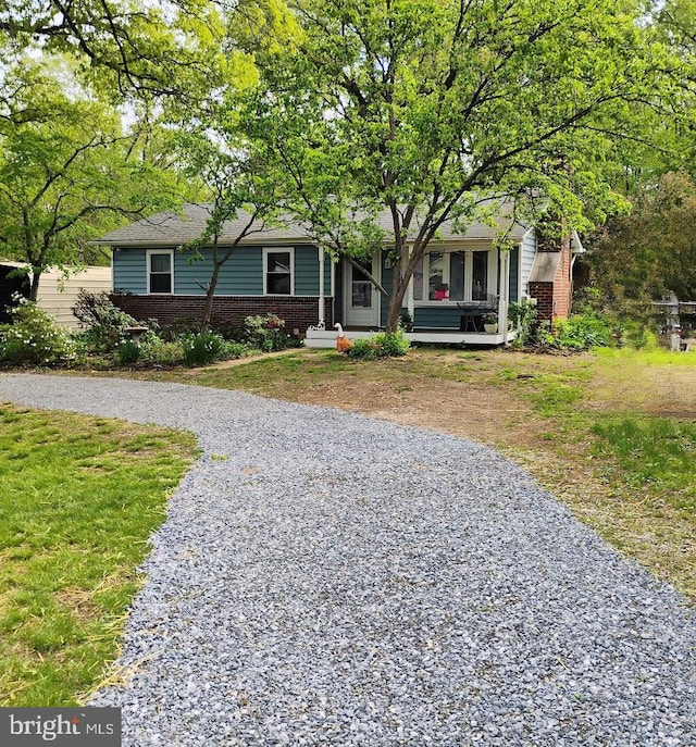 view of front of house featuring brick siding, driveway, a front yard, and a porch
