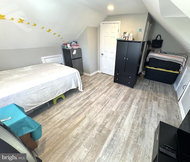 3207 Randall Rd, Suitland, MD 20746 - bedroom featuring baseboards, freestanding refrigerator, wood finished floors, and vaulted ceiling