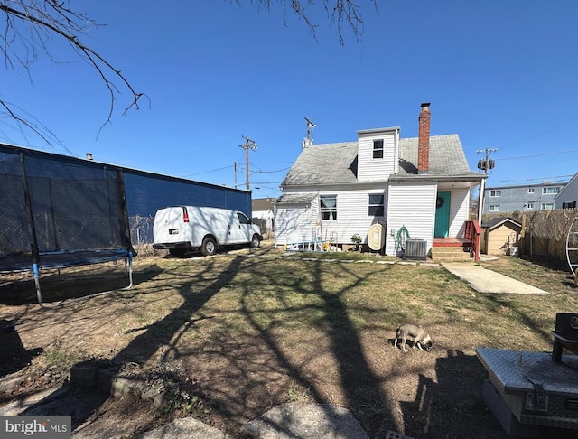 3207 Randall Rd, Suitland, MD 20746 - rear view of house featuring a chimney, a trampoline, a lawn, central AC unit, and a shed