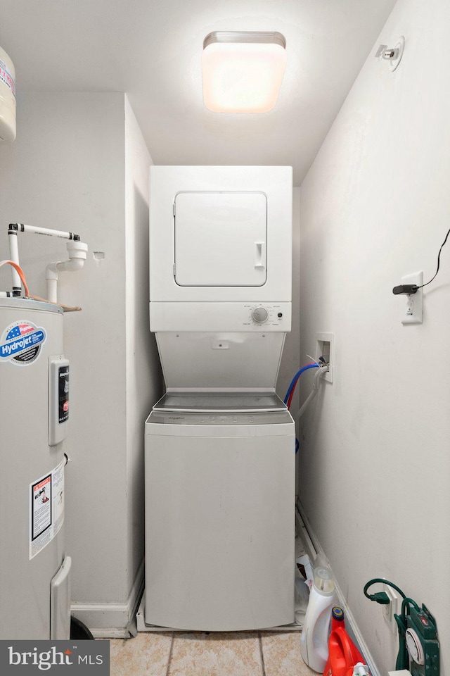 clothes washing area with laundry area, baseboards, electric water heater, and stacked washer / drying machine