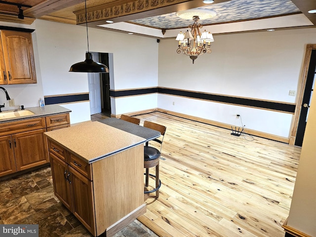 kitchen featuring a sink, a chandelier, a breakfast bar, hanging light fixtures, and dark wood-style flooring