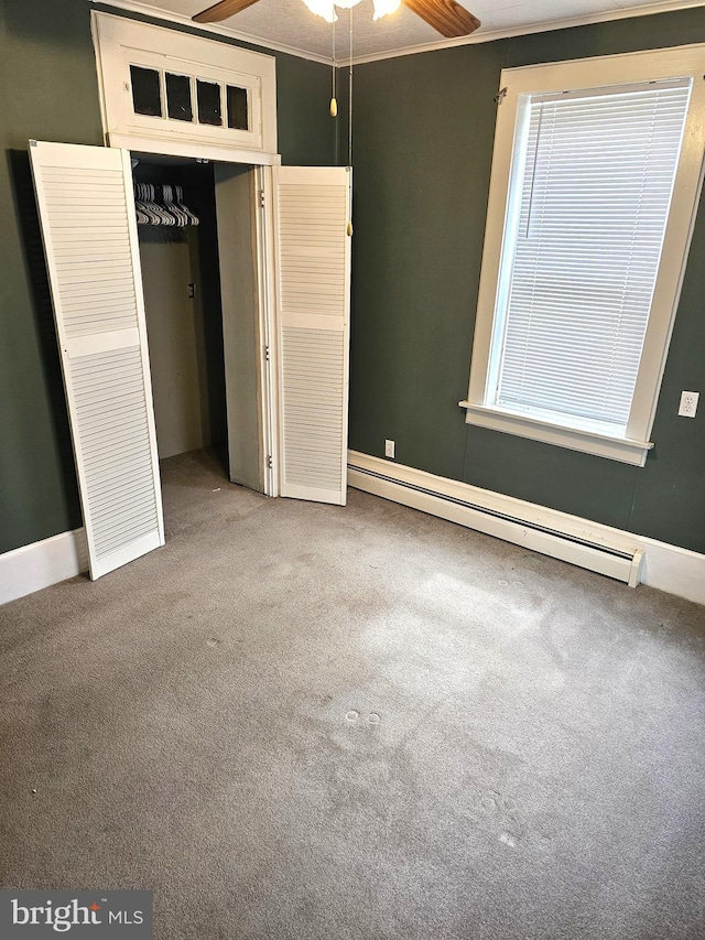 unfurnished bedroom featuring a closet, carpet floors, ornamental molding, and a baseboard heating unit
