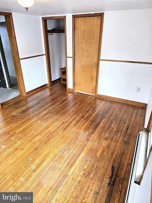 unfurnished bedroom featuring baseboards, wainscoting, and hardwood / wood-style flooring