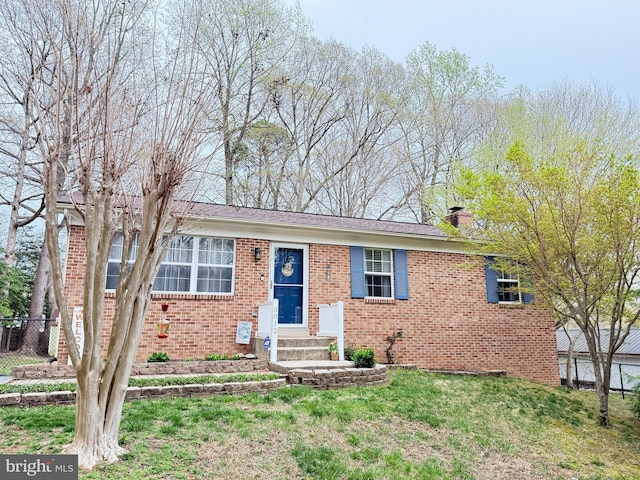 view of front of home featuring fence, a front lawn, brick siding, entry steps, and a chimney