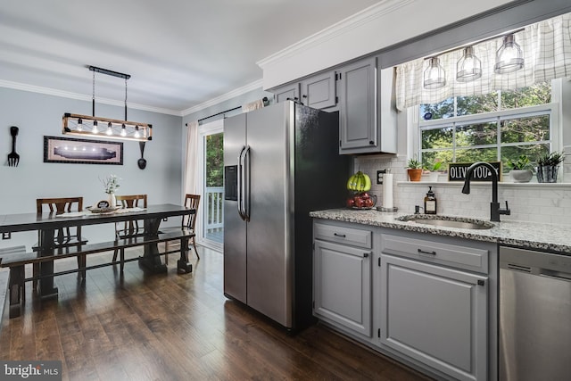 kitchen featuring crown molding, tasteful backsplash, a sink, appliances with stainless steel finishes, and gray cabinetry