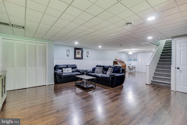 living room featuring dark wood finished floors, ceiling fan, and stairs