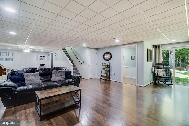 living area with stairs, a ceiling fan, baseboards, and wood finished floors