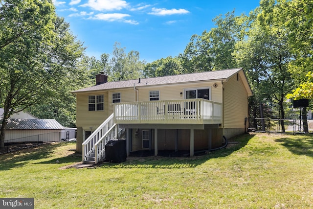 rear view of house featuring fence, a deck, a chimney, a yard, and stairway
