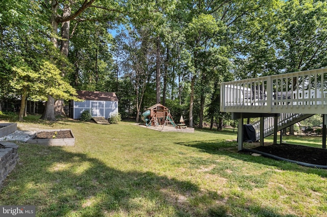 view of yard featuring a storage unit, a wooden deck, a vegetable garden, a playground, and an outdoor structure