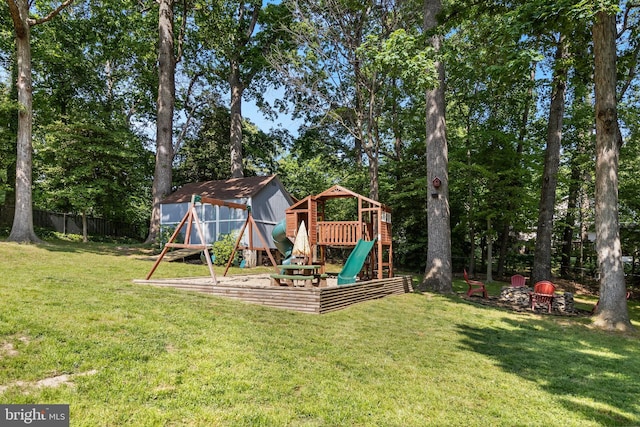 view of jungle gym featuring fence, a storage unit, an outdoor structure, and a yard