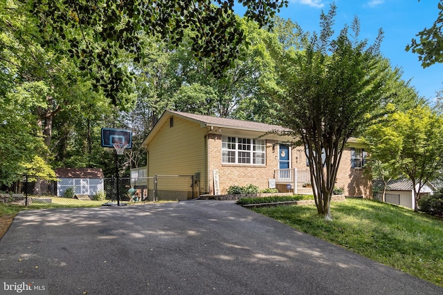 view of front of house featuring driveway, a front yard, a gate, brick siding, and fence