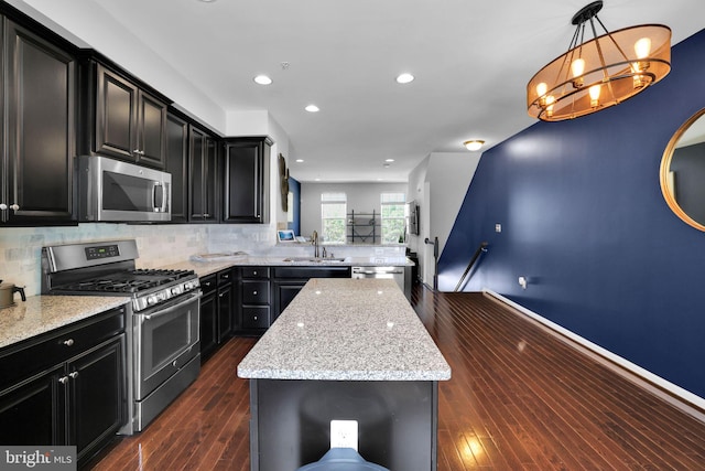kitchen featuring decorative backsplash, appliances with stainless steel finishes, dark cabinetry, and a kitchen island