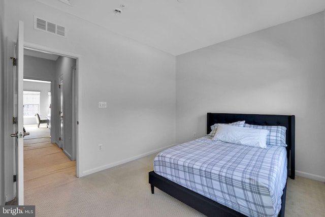 bedroom featuring visible vents, baseboards, and light carpet