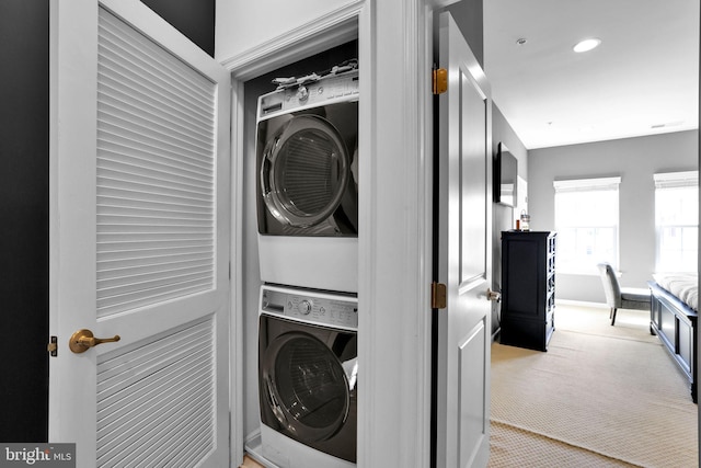 laundry area with stacked washer and dryer, light carpet, recessed lighting, and laundry area