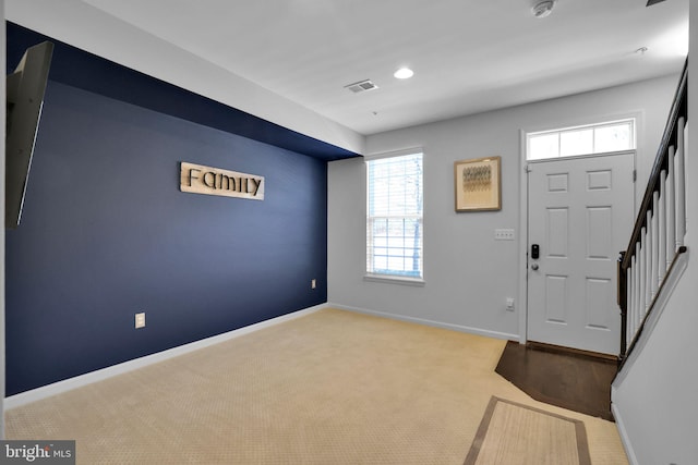 entrance foyer with baseboards, carpet floors, stairway, and a healthy amount of sunlight