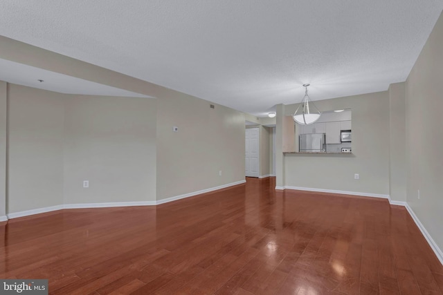 unfurnished living room featuring hardwood / wood-style flooring, baseboards, and a textured ceiling