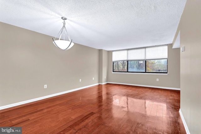 spare room with baseboards, a textured ceiling, and wood finished floors