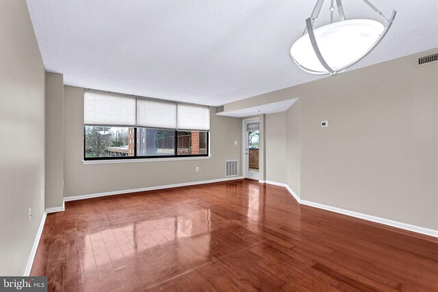 unfurnished living room featuring baseboards, visible vents, and wood finished floors
