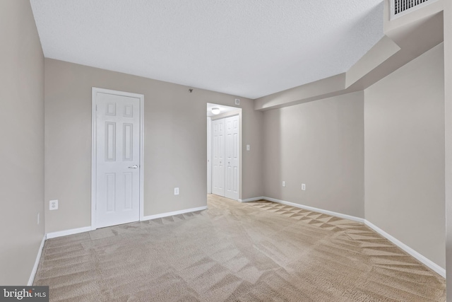 unfurnished bedroom featuring a closet, carpet floors, a textured ceiling, baseboards, and visible vents