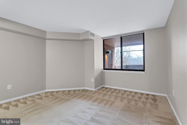 carpeted empty room featuring baseboards, visible vents, and a textured ceiling