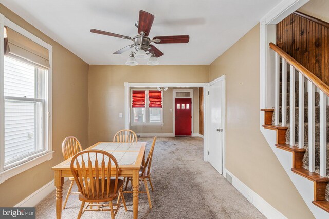 dining room featuring baseboards, stairs, a ceiling fan, and carpet floors