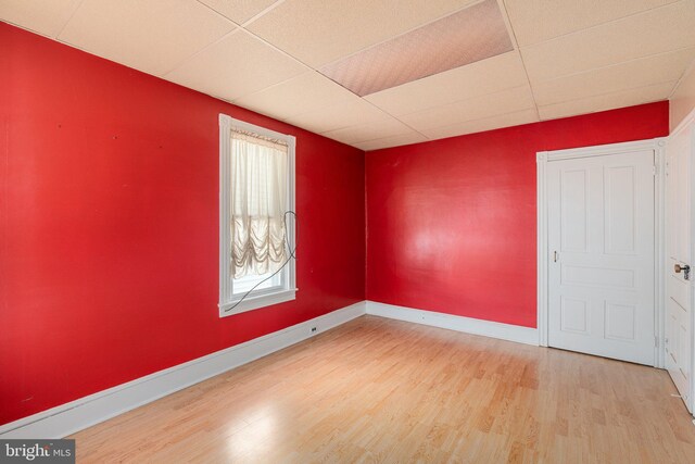empty room featuring baseboards, wood finished floors, and a paneled ceiling