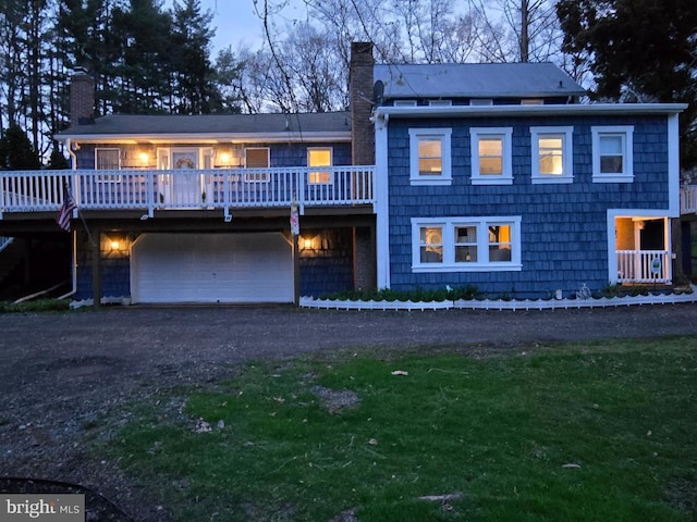 view of front of home featuring an attached garage, dirt driveway, a chimney, and a deck