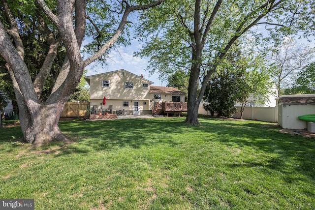view of yard featuring a fenced backyard, a wooden deck, and an outbuilding
