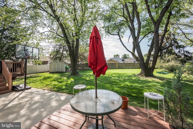 deck featuring an outdoor structure, a fenced backyard, a storage unit, a yard, and a patio