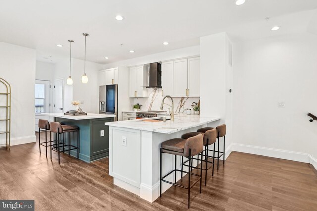 322 56th St NE, Washington, DC 20019 - kitchen with a breakfast bar area, a sink, wood finished floors, wall chimney range hood, and white cabinets