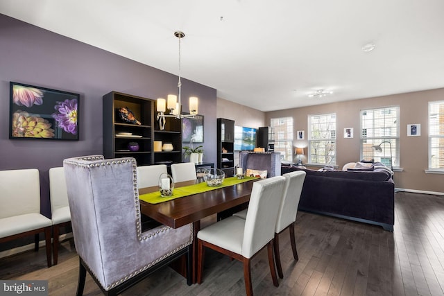 dining space featuring a chandelier, baseboards, and dark wood finished floors