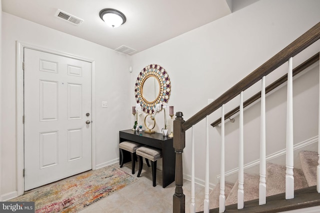tiled foyer entrance featuring visible vents, baseboards, and stairs
