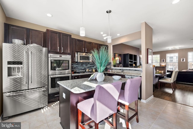 kitchen featuring tasteful backsplash, dark brown cabinets, a sink, and stainless steel appliances