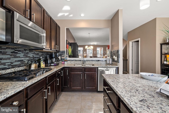 kitchen featuring tasteful backsplash, an inviting chandelier, dark brown cabinets, stainless steel appliances, and a sink