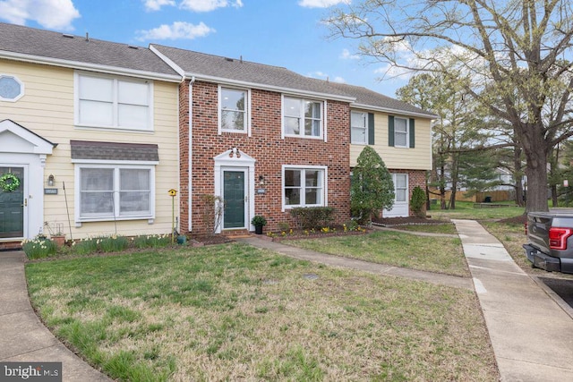 townhome / multi-family property with a front lawn and brick siding