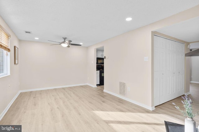 interior space with light wood-style floors, ceiling fan, and visible vents