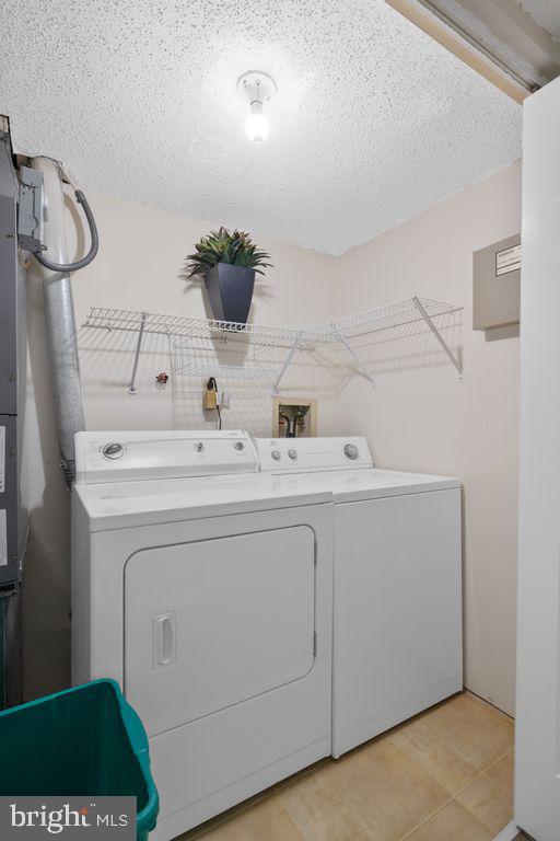 clothes washing area with washing machine and dryer, laundry area, and a textured ceiling